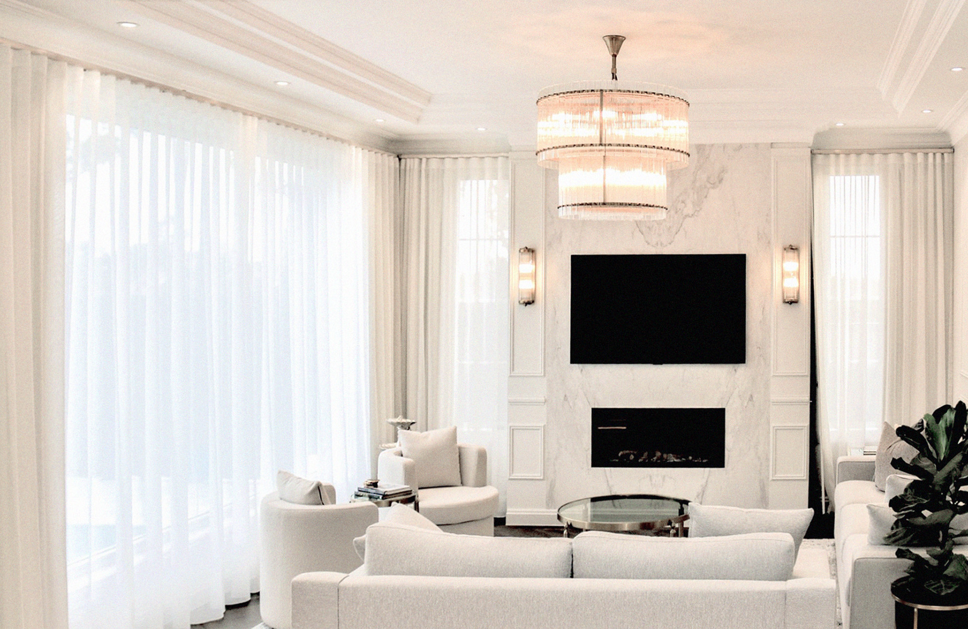 Sheer curtains framing a marble fireplace in a white living room