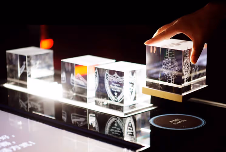 A hand placing a glass cube on an interactive panel.