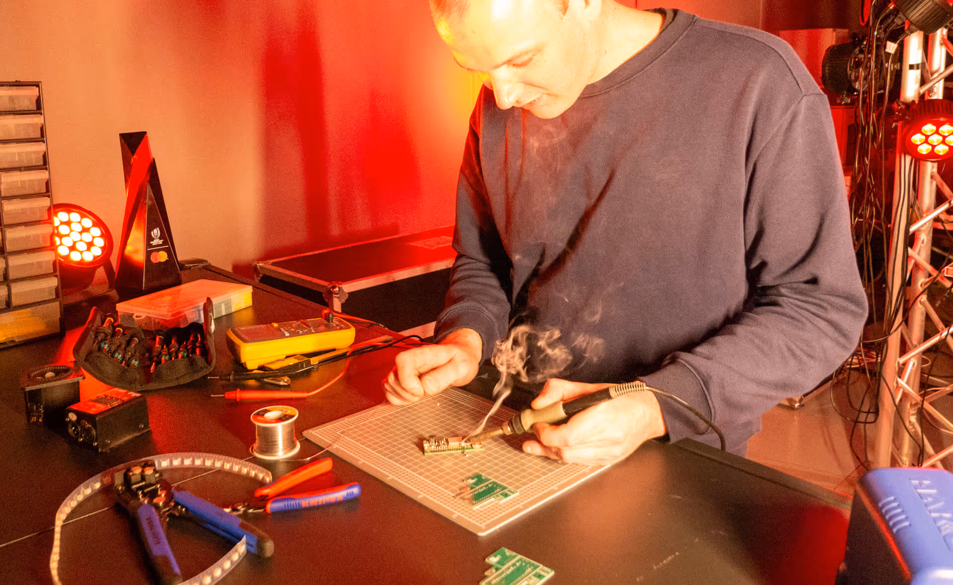 A person soldering at a workshop bench.