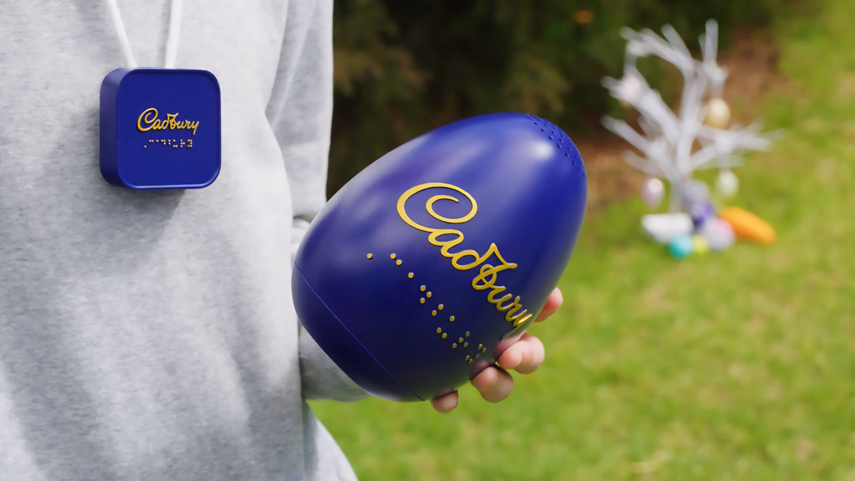 A person holding a giant purple Cadbury Easter egg.