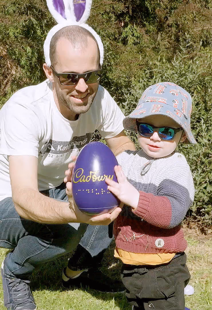 An adult and child holding a giant Cadbury Easter egg.