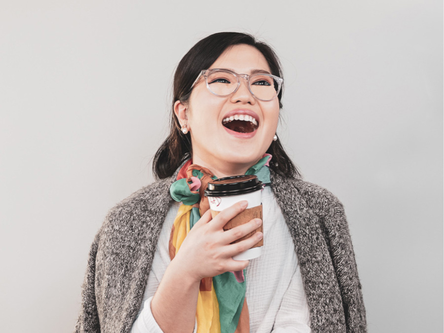 Portrait of Cee against a light gray background holding a coffee