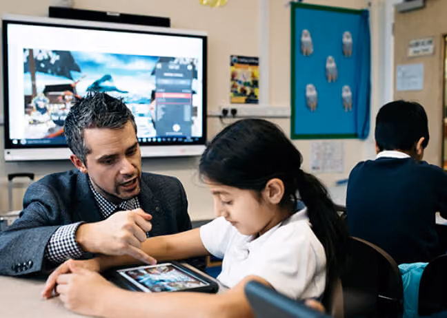 A teacher demonstrating how to use classroom technology to a student.
