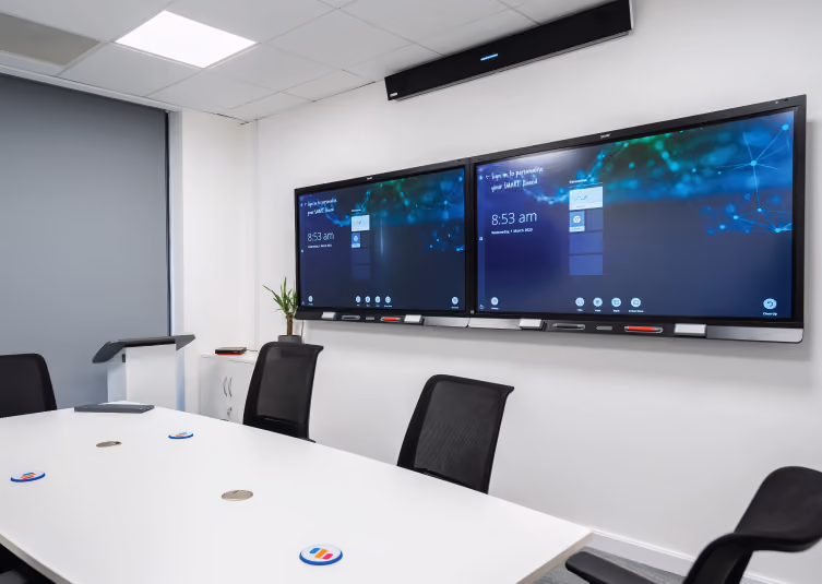 A conference room with two interactive touchscreens on the wall.