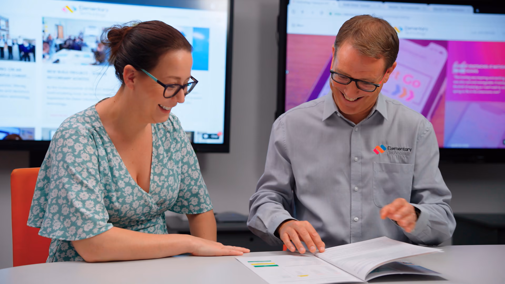 A man and a woman laughing together whilst reviewing a document in at a table
