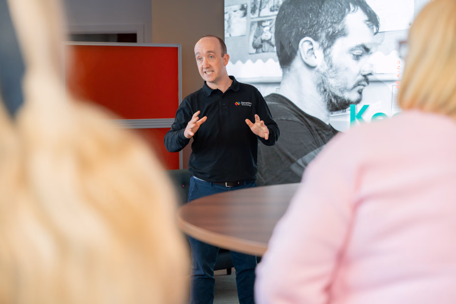 A man explaining to a room how to use an interactive touchscreen for schools.
