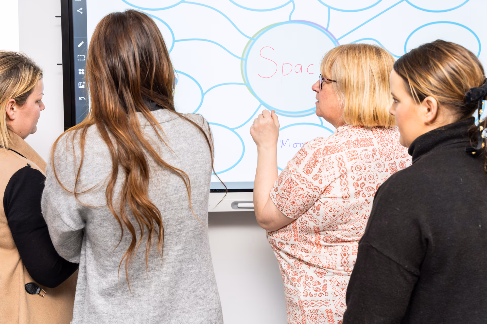 Four teachers using an interactive touchscreen.