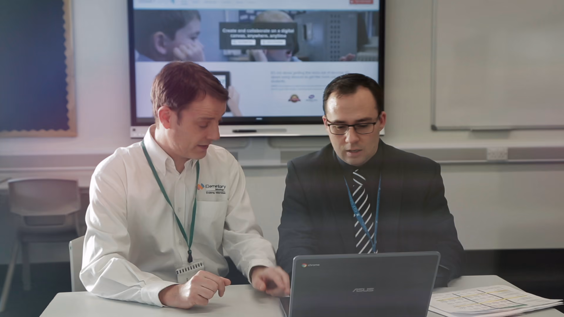 A headteacher being shown how to use classroom technology.