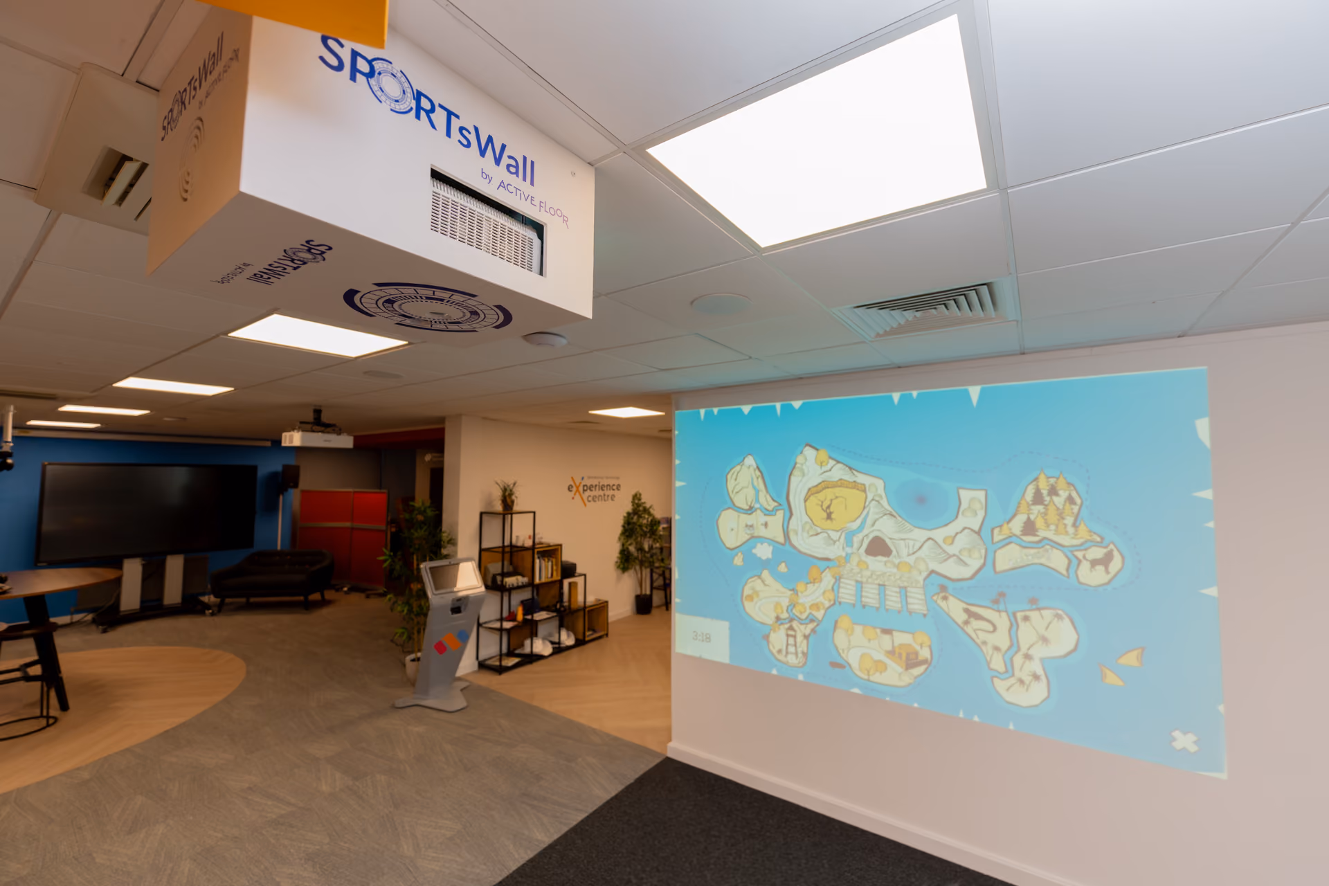Modern office space with a projected map of islands on a white wall and a white SportsWall device mounted on the ceiling.