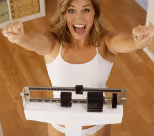 A happy woman smiling as she stands on a scale.