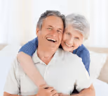 A happy elderly couple hugging and smiling.