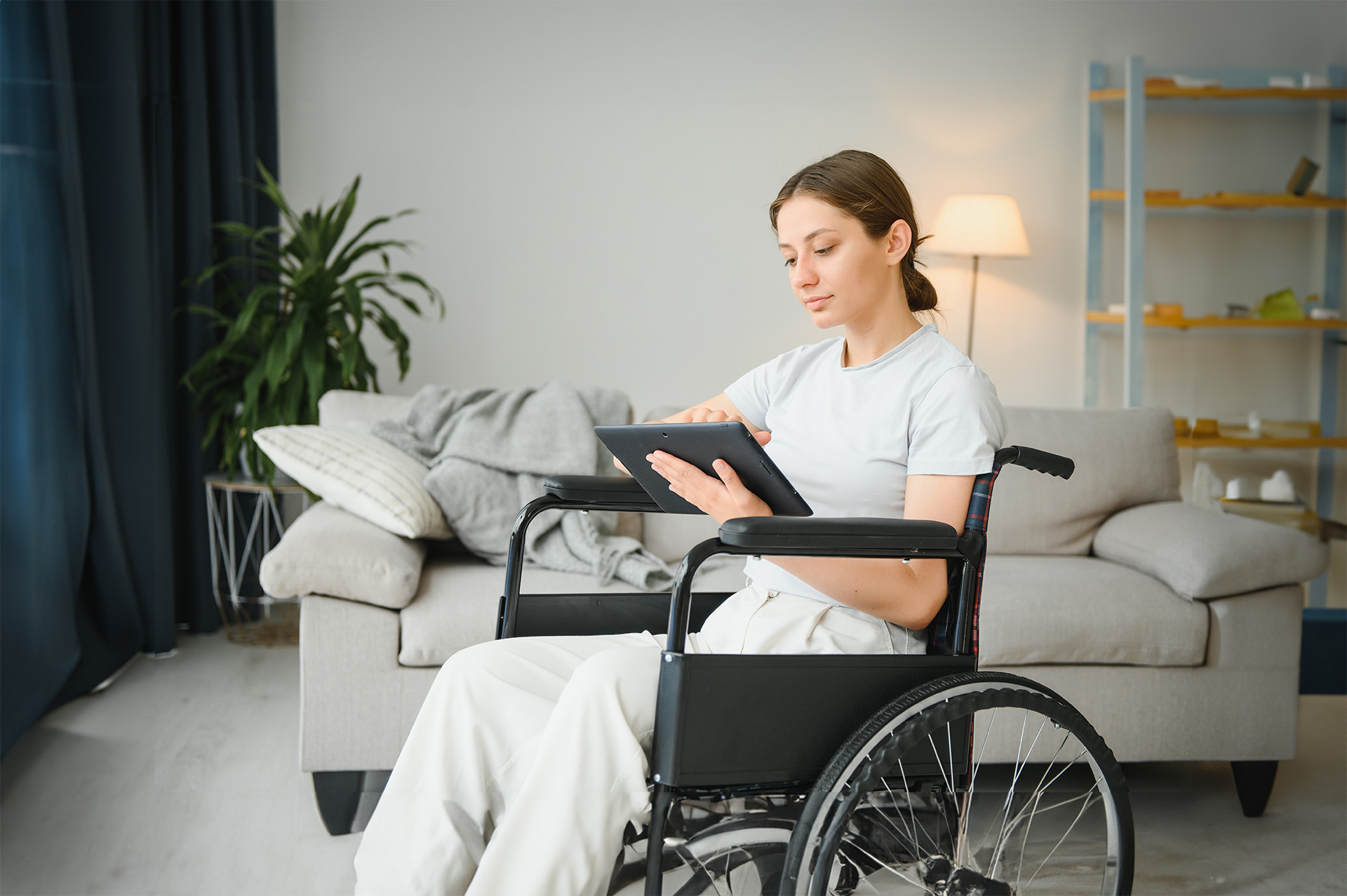 Woman in a wheelchair checking a message on her ipad.