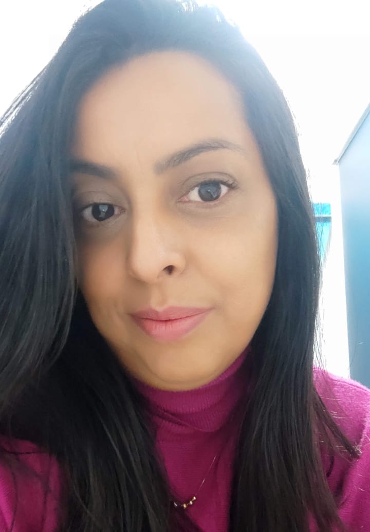 Retrato próximo de uma mulher com cabelo preto liso usando blusa de gola alta rosa escuro.