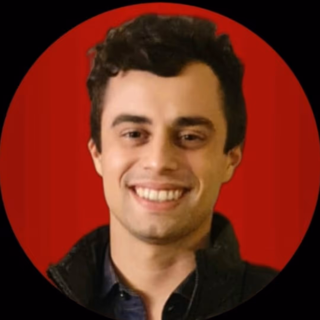 Retrato de um homem jovem sorridente com cabelo curto e escuro, vestindo jaqueta preta, com fundo vermelho circular.