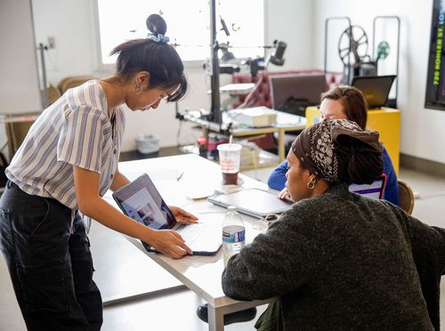 Student presenting design work on her laptop to two instructors at Inner City Arts.