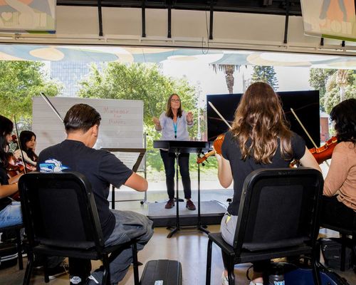 Students playing instruments with conductor.
