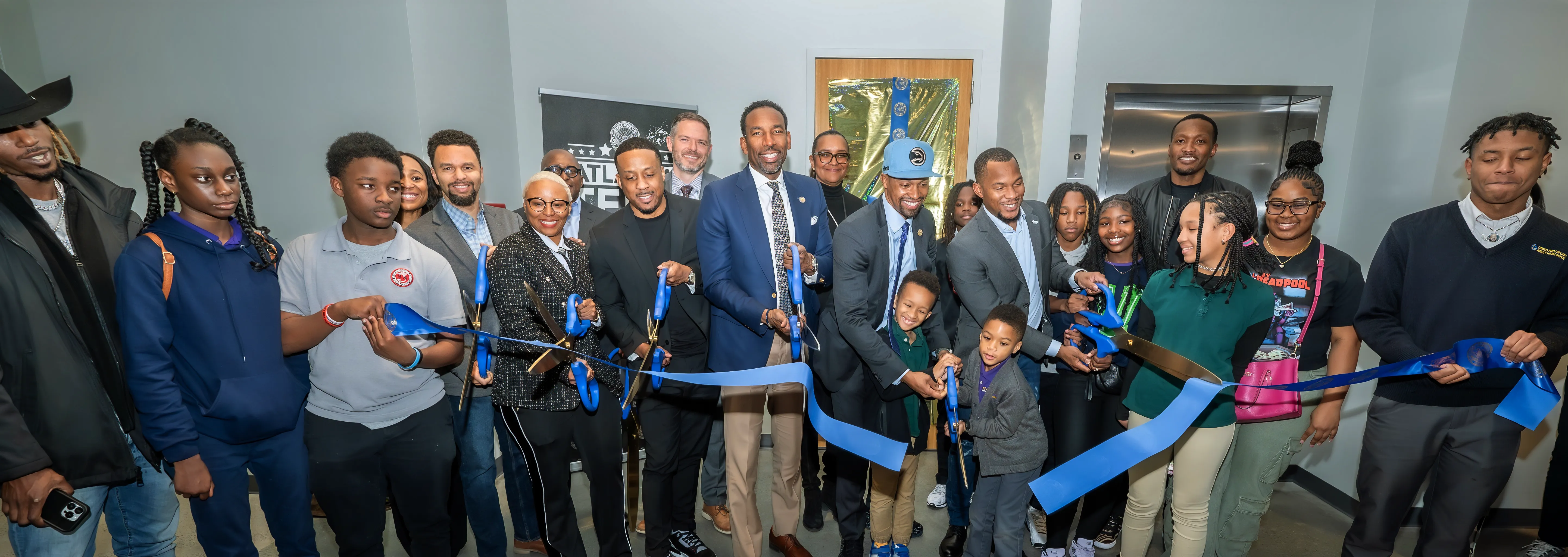 Atlanta Mayor Andre Dickens, alongside city officials, students, and community members, cuts a blue ribbon at a ceremony celebrating a new technology-focused initiative in Atlanta.