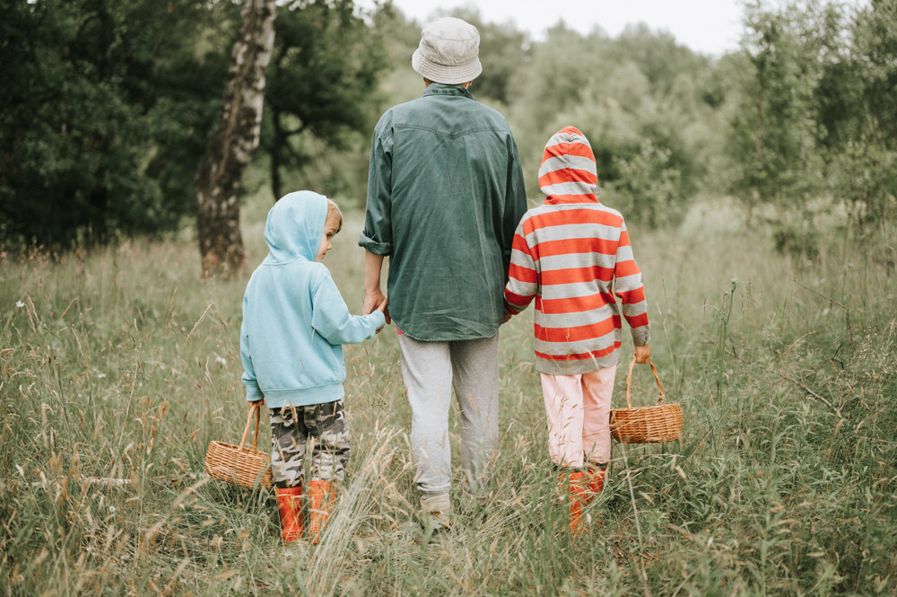 Father with children walking through a field.