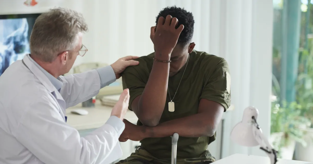 Doctor comforting a veteran showing signs of PTSD and anxiety during a counseling appointment.