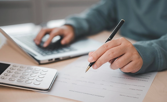 A person sitting at a table with a laptop and a calculator.