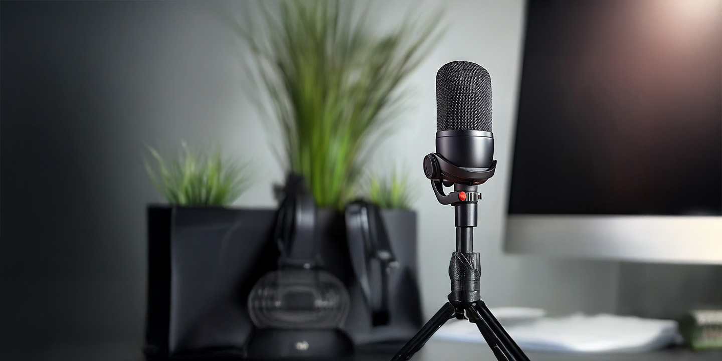 Podcast set-up with microphone on desk and computer in background
