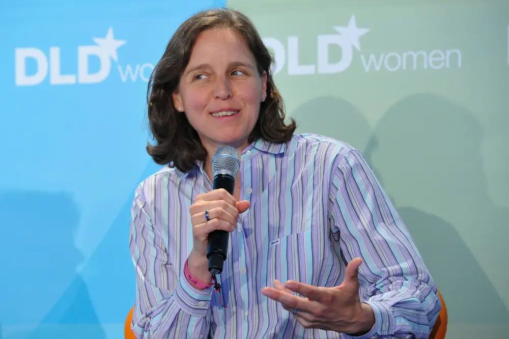 Megan Smith speaking at DLDwomen, wearing a striped shirt and holding a microphone, mid-discussion on stage.