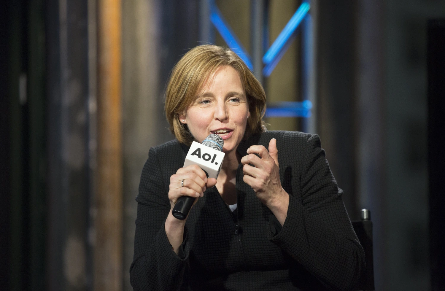 Megan Smith speaking at an AOL event, holding a microphone and gesturing during a live discussion