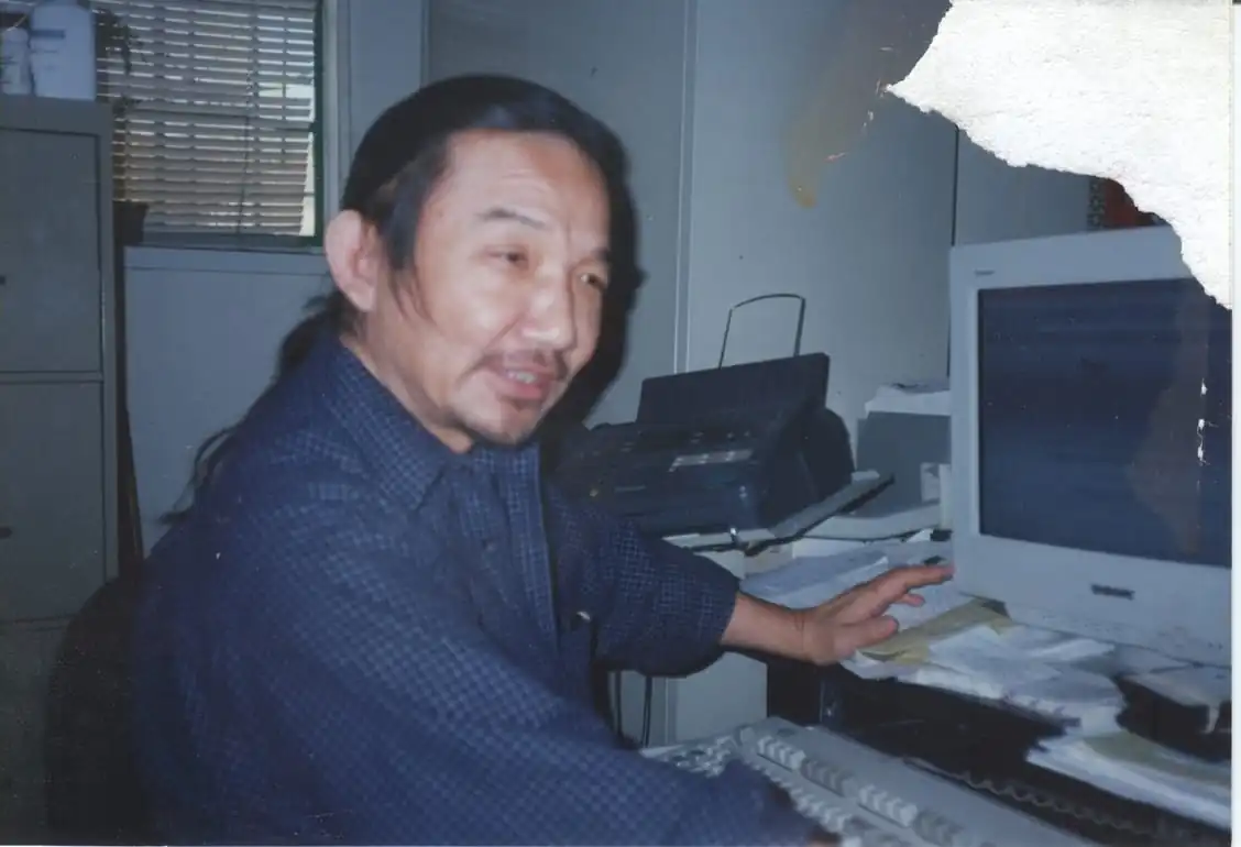 Kiyoshi Kuromiya sitting at his desk, working with papers and books.