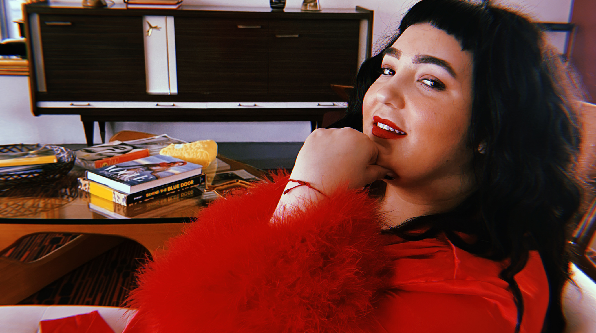 Anna from HoneyWhippedFeta in red feather dress with red lipstick - sensual fragrance guide author and fragrance expert