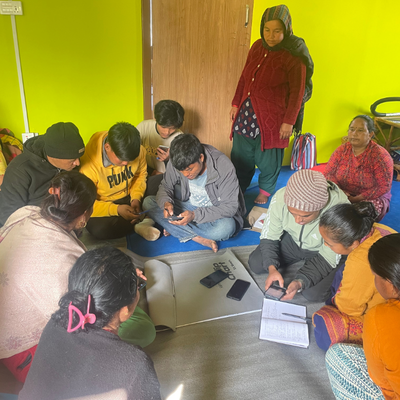 A group of people are working with a local facilitator who introduces a mobile-based agricultural application to the farmers and provides them with hands-on training