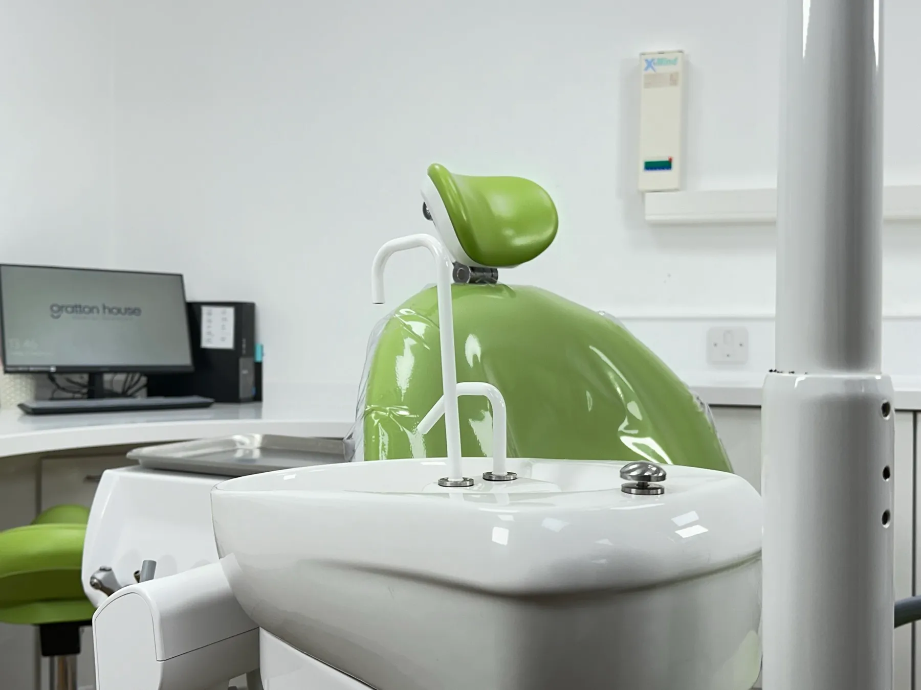 A green and white chair in a dental office