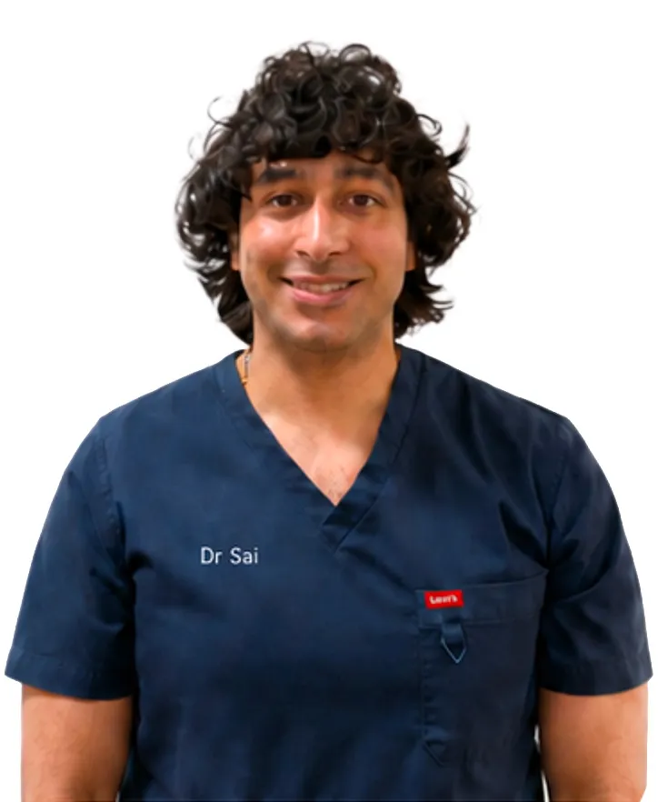 Smiling man with curly dark hair wearing navy blue medical scrubs with 'Dr Sai' embroidered on the chest.
