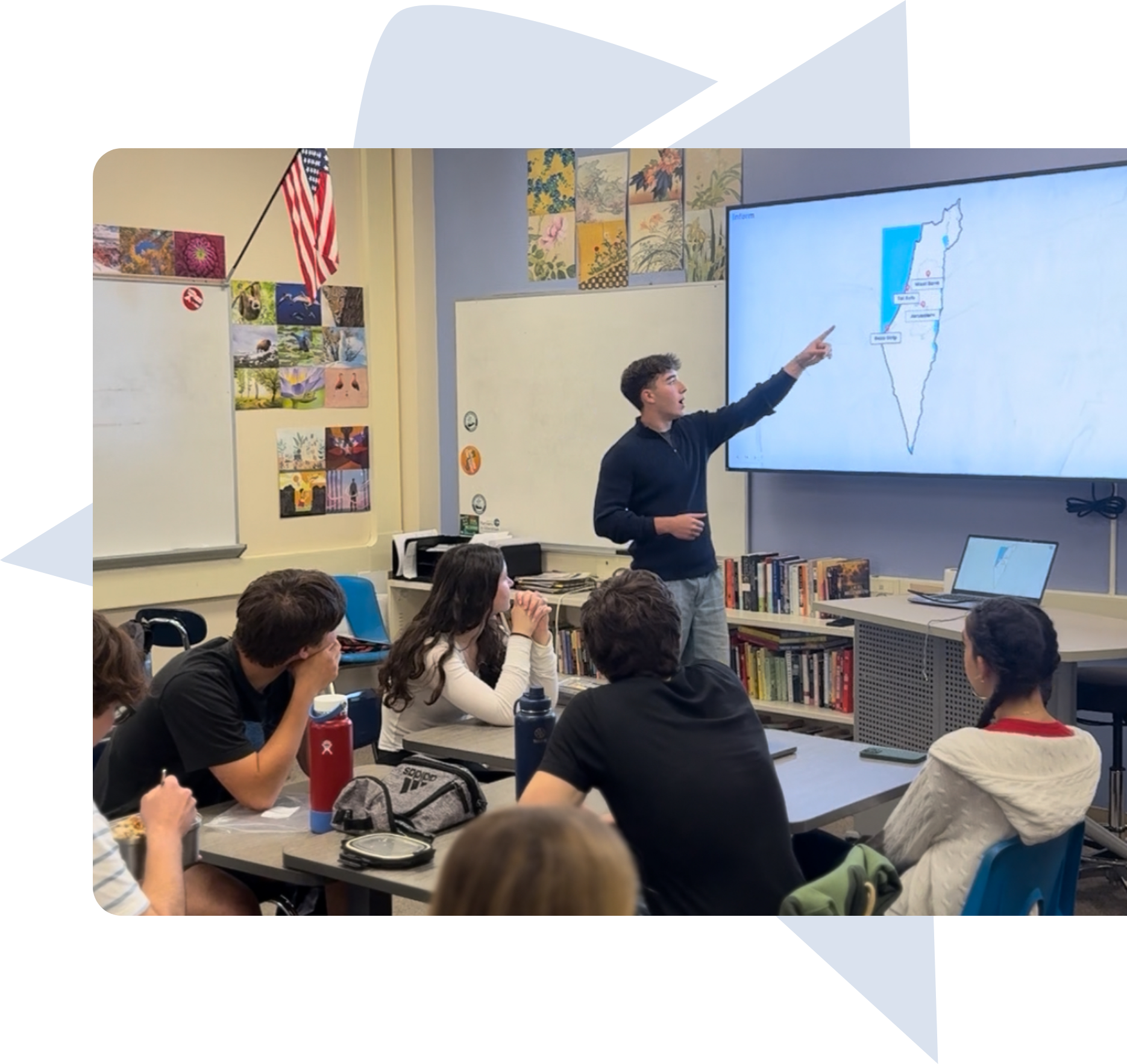 Two young men speaking on stage to an audience seated in a tent with purple backdrop featuring logos.