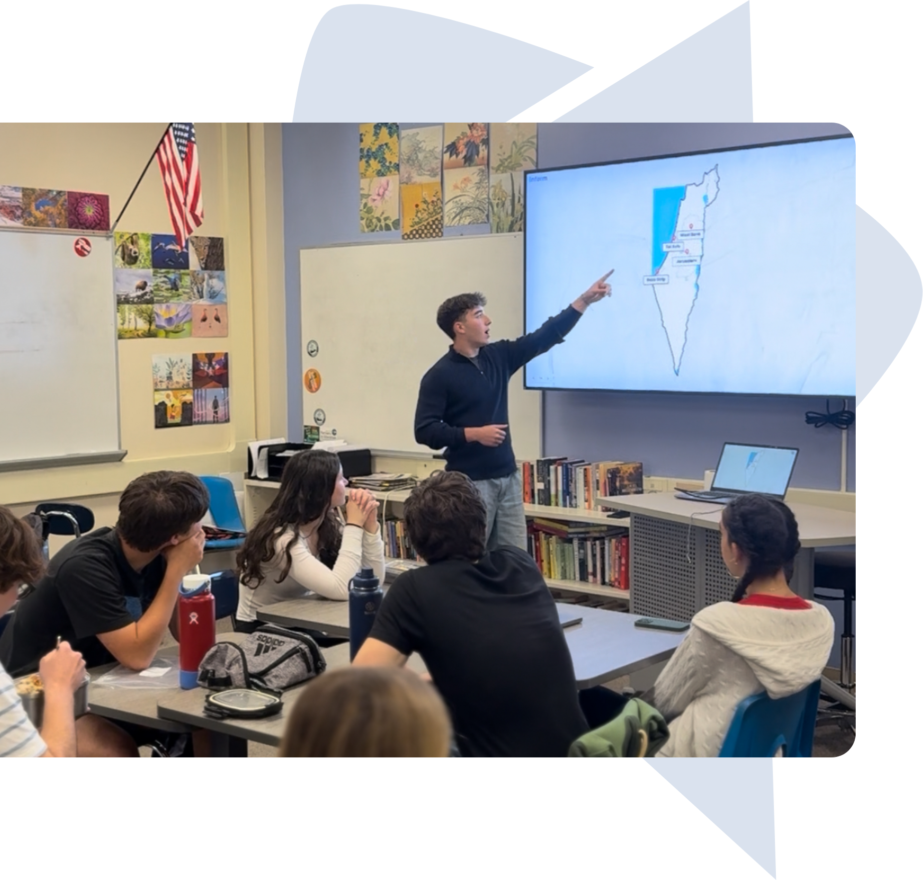 Two young men speaking on stage to an audience seated in a tent with purple backdrop featuring logos.