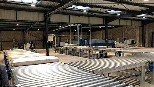 Interior view of Recyc Matelas’ industrial recycling facility, featuring large conveyor systems and automated machinery inside a spacious warehouse. Several mattresses move through the processing line, illustrating the company’s recycling operations. Using Bonx, Recyc Matelas manages weighbridge integration, real-time stock tracking, production scheduling, compliance, and profitability with greater flexibility than traditional ERP systems.