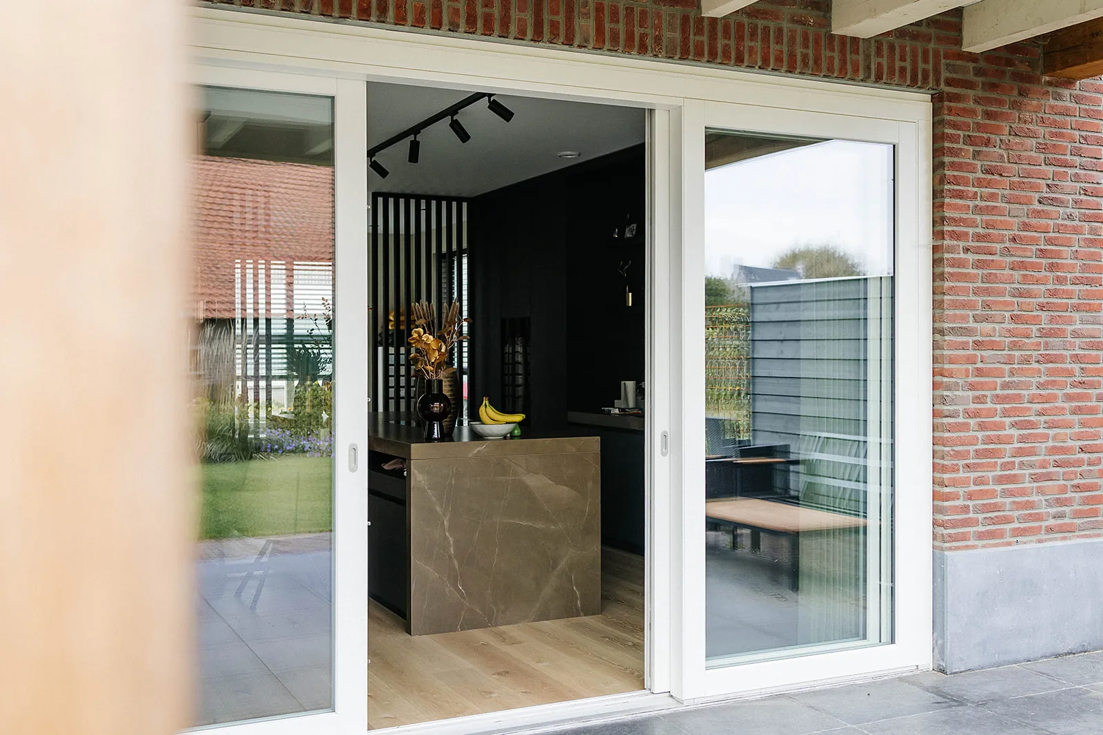 Geopende witte kunststof schuifpui met zicht op een moderne keuken