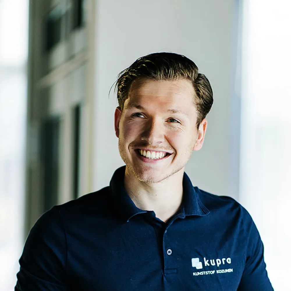 Portret van een lachende Kupro-medewerker in een donkerblauwe Kupro-polo