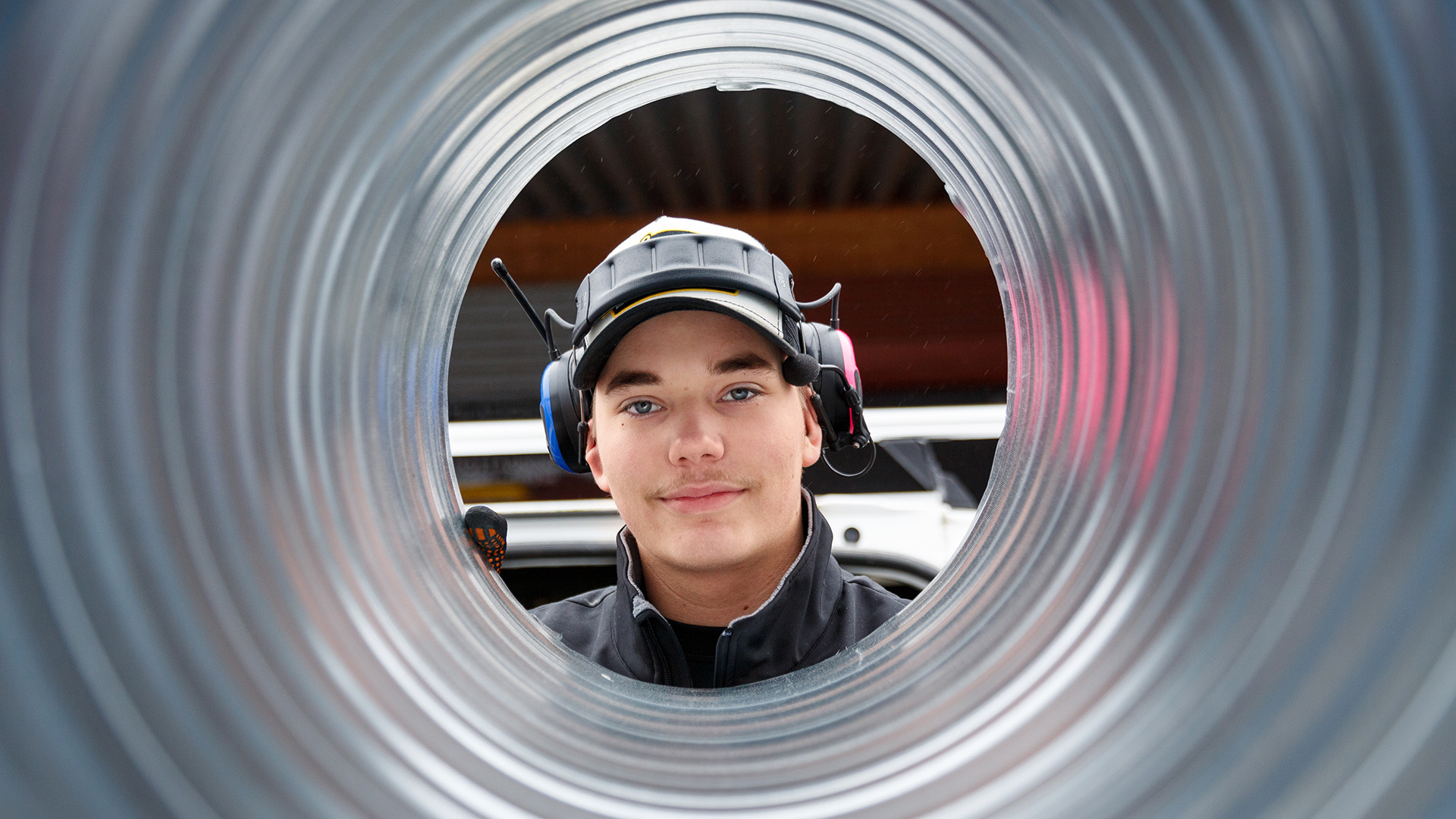 Tre personer tittar in i kameran genom ett rör hållandes i handen