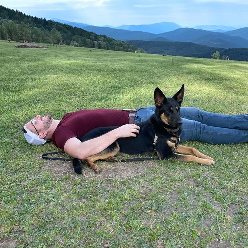 James (Harless) Reid and his dog Khaleesi laying in the grass.