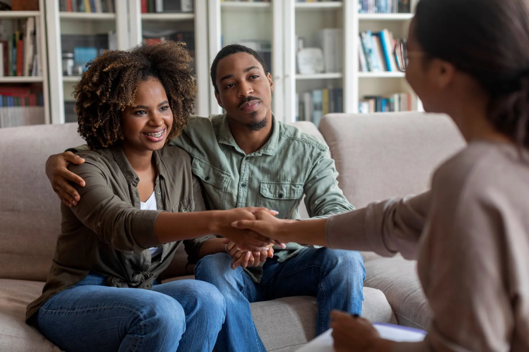 Couple sitting on couch talking with therapist during a couples therapy meeting.