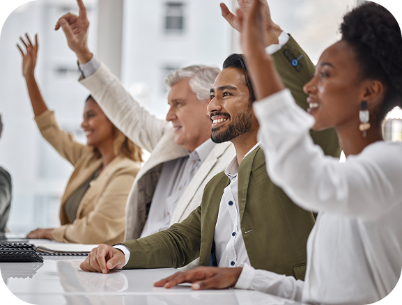 Diverse group of four business professionals smiling and raising their hands in a meeting.
