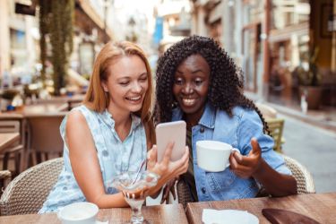 Woman showing her mobile phone to her friend