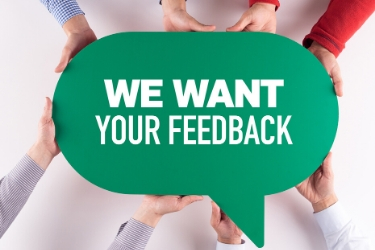 People holding a speech bubble with the sentence "We Want your Feedback"