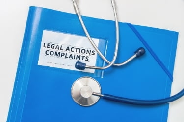Legal Actions and Complaints in a blue folder with a stethoscope