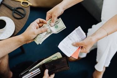 Someone giving cash to another person