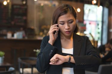 Businesswoman checking her watch during a phone call
