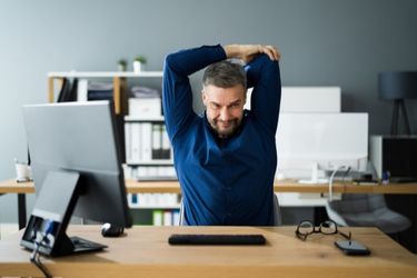 Man stretching in front of the computer