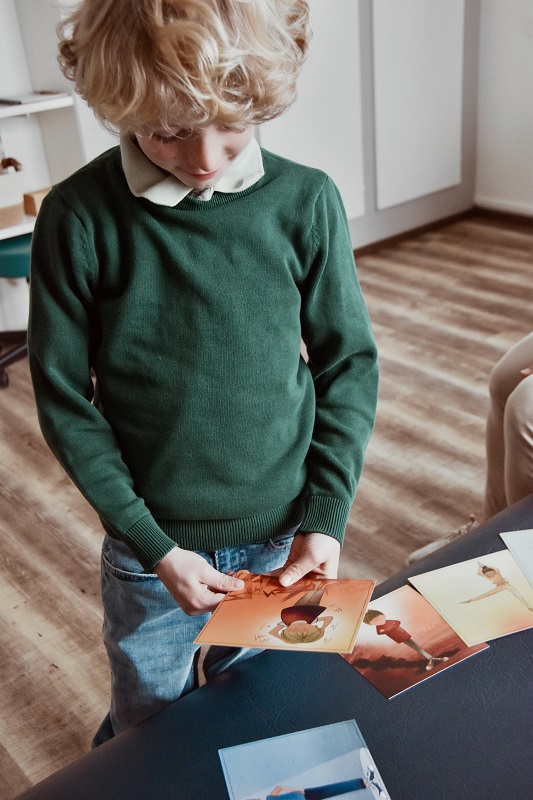 A boy choosing a card with feelings drawn on it.