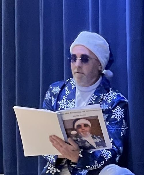 A man in a blue suit reading a book