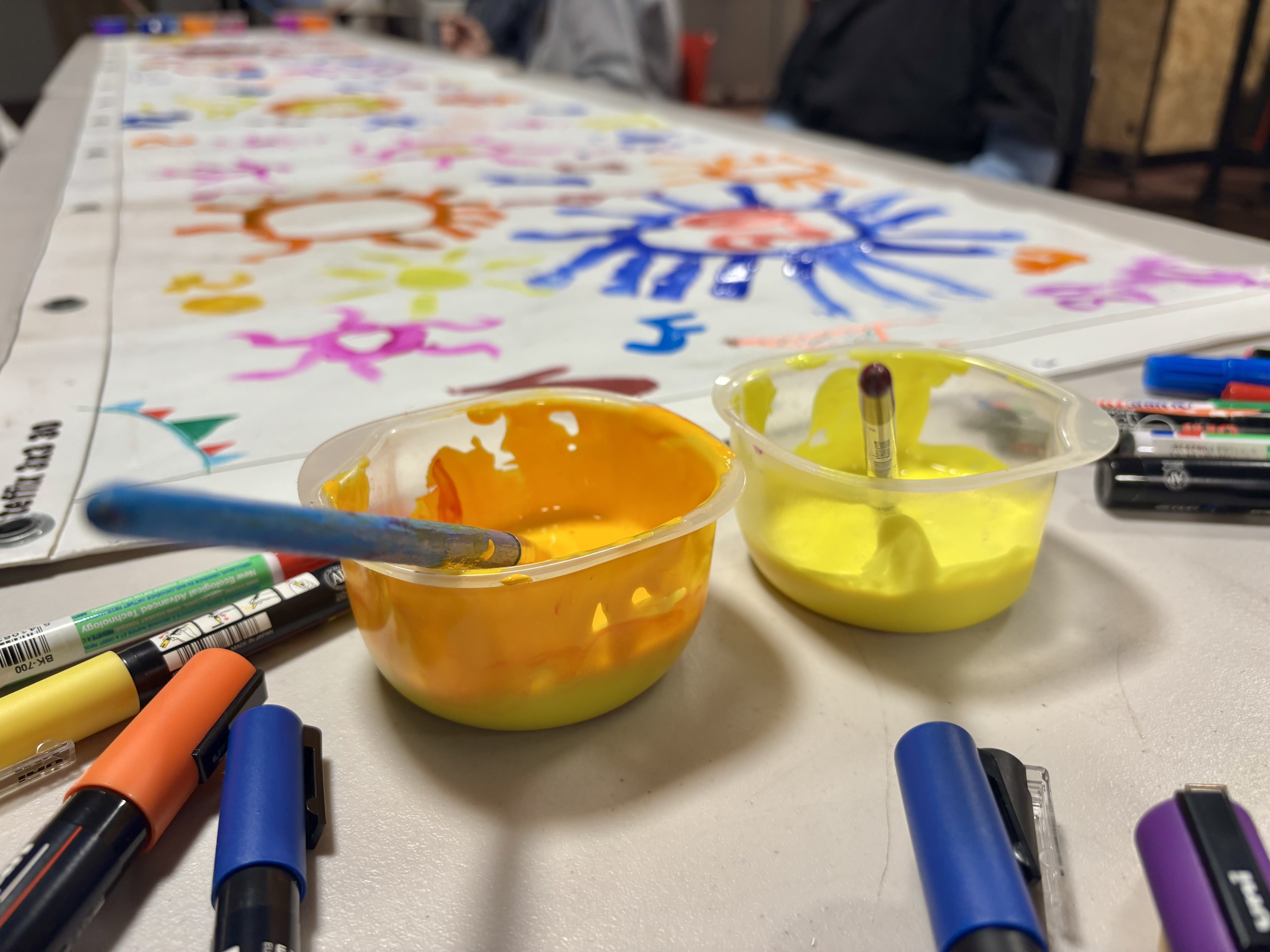 a fresco and pots of paint with brushes and markers